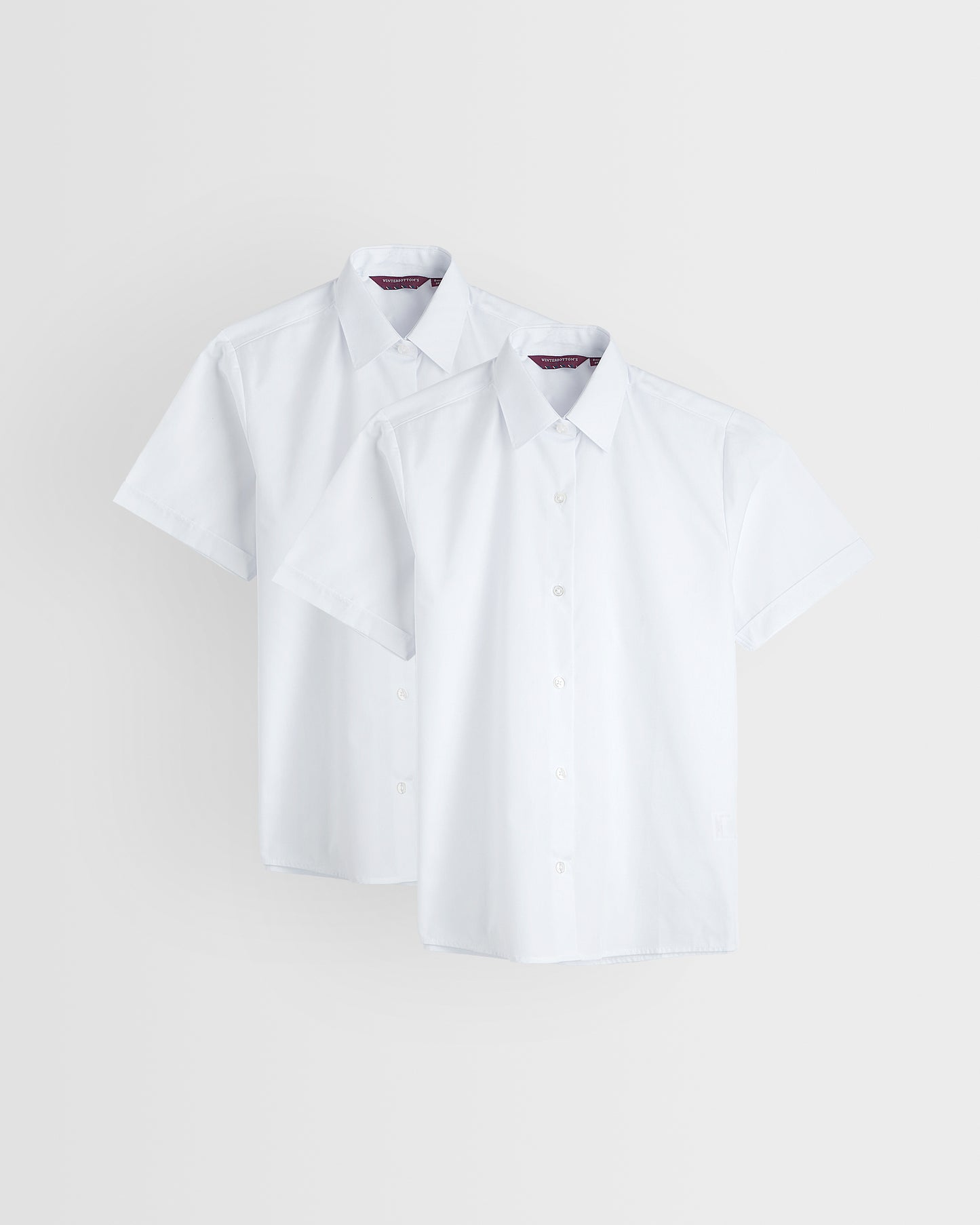 Two white short sleeve girls' shirts with collars, displayed against a white background.