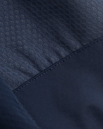 Close-up detail of a dark navy blue garment showing two different fabric textures: a textured mesh-like upper panel and a smoother lower panel with matching dark stitching.