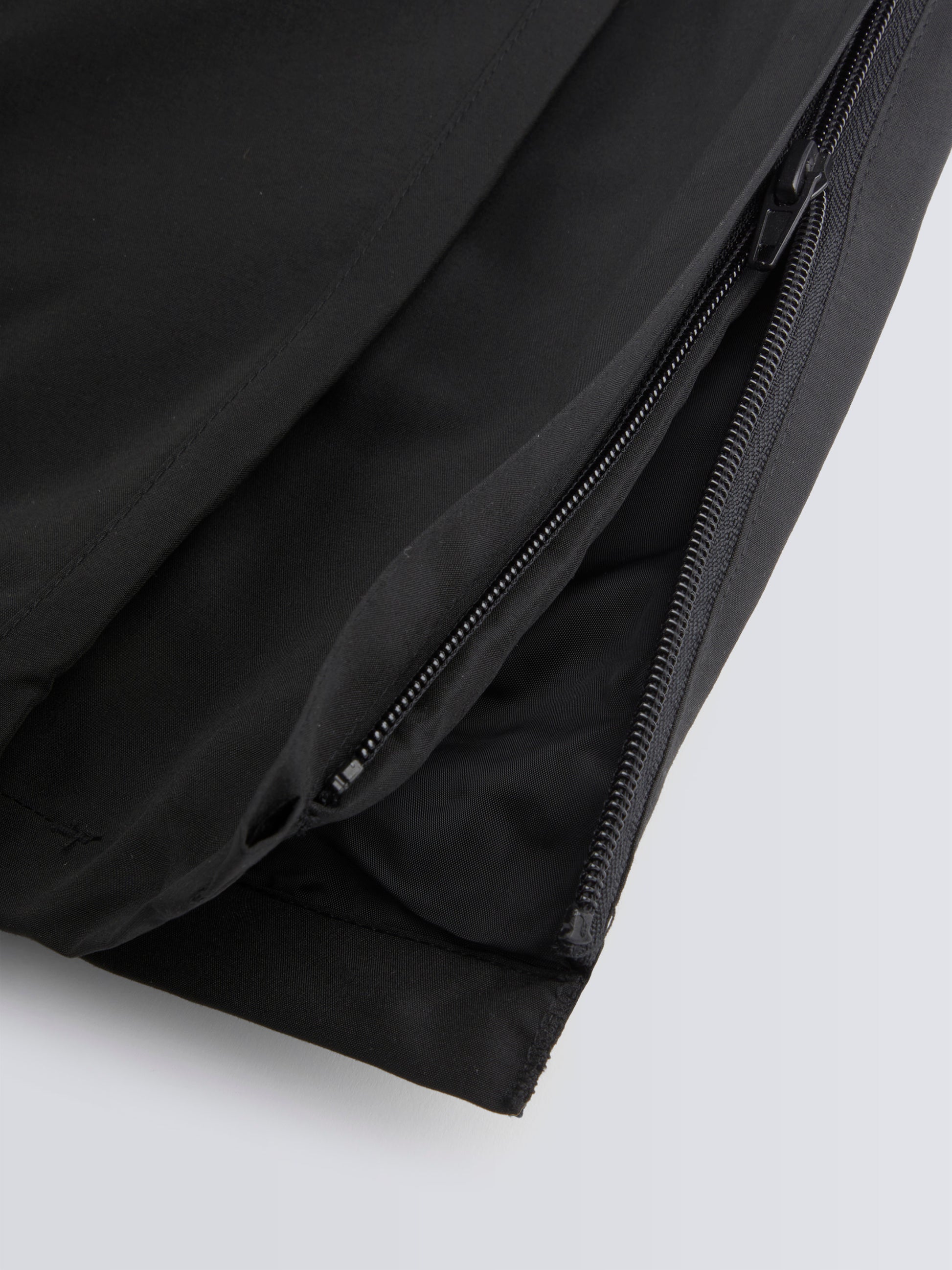 Close-up of black track pant with a zipper on a light grey background