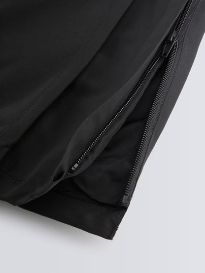 Close-up of black track pant with a zipper on a light grey background