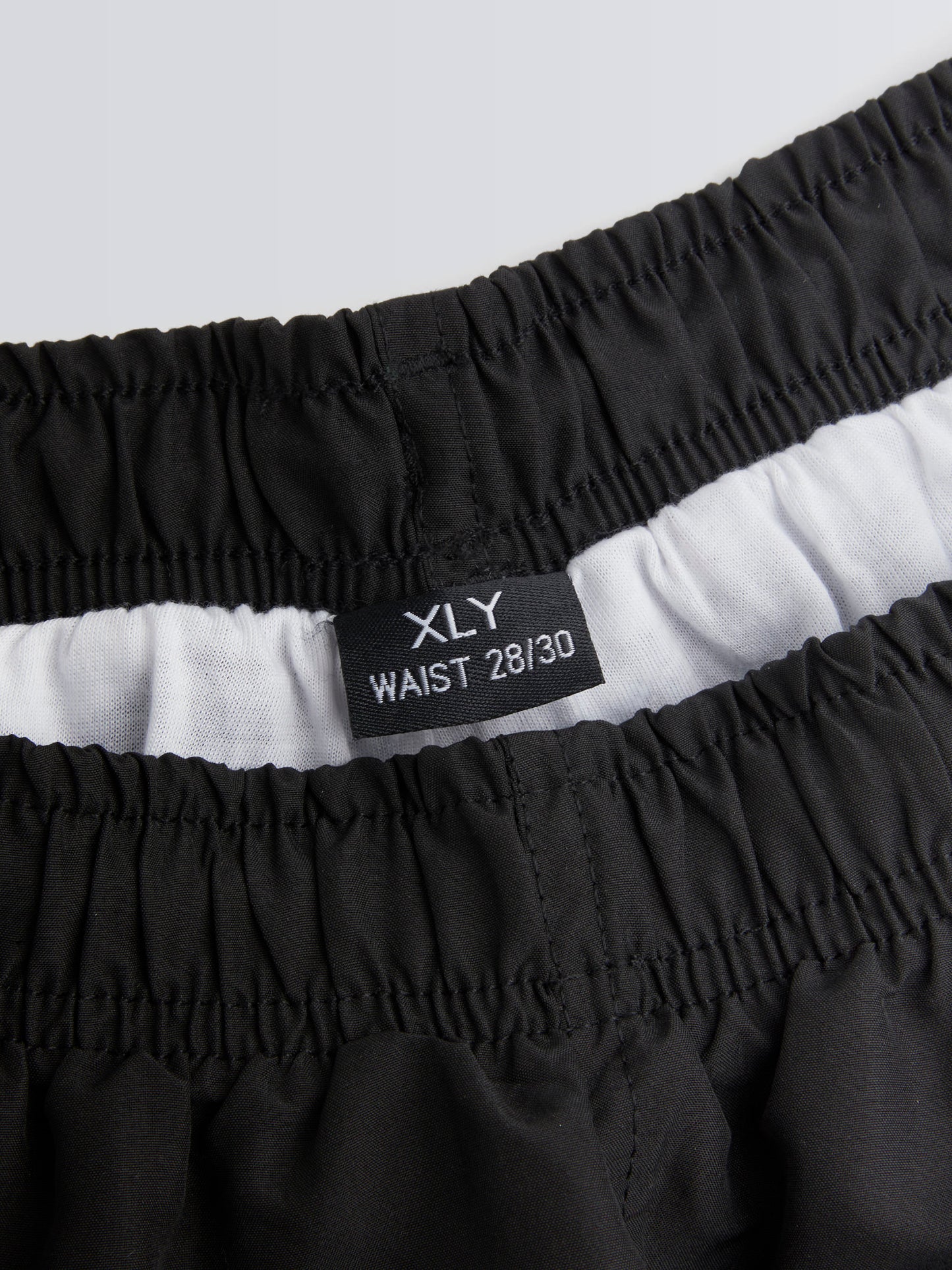 Black shorts with waistband label on a light grey background