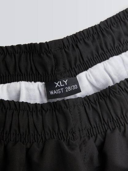 Black shorts with waistband label on a light grey background