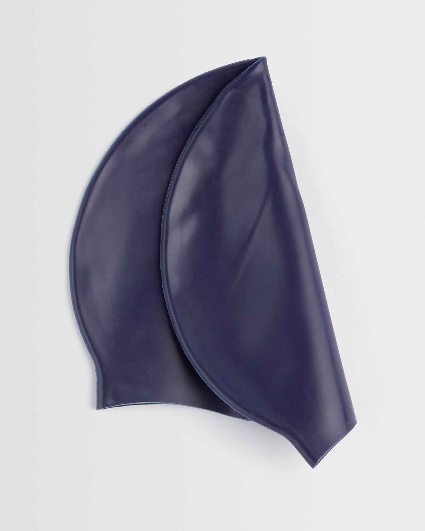 Folded navy silicone swim cap placed on a white background.