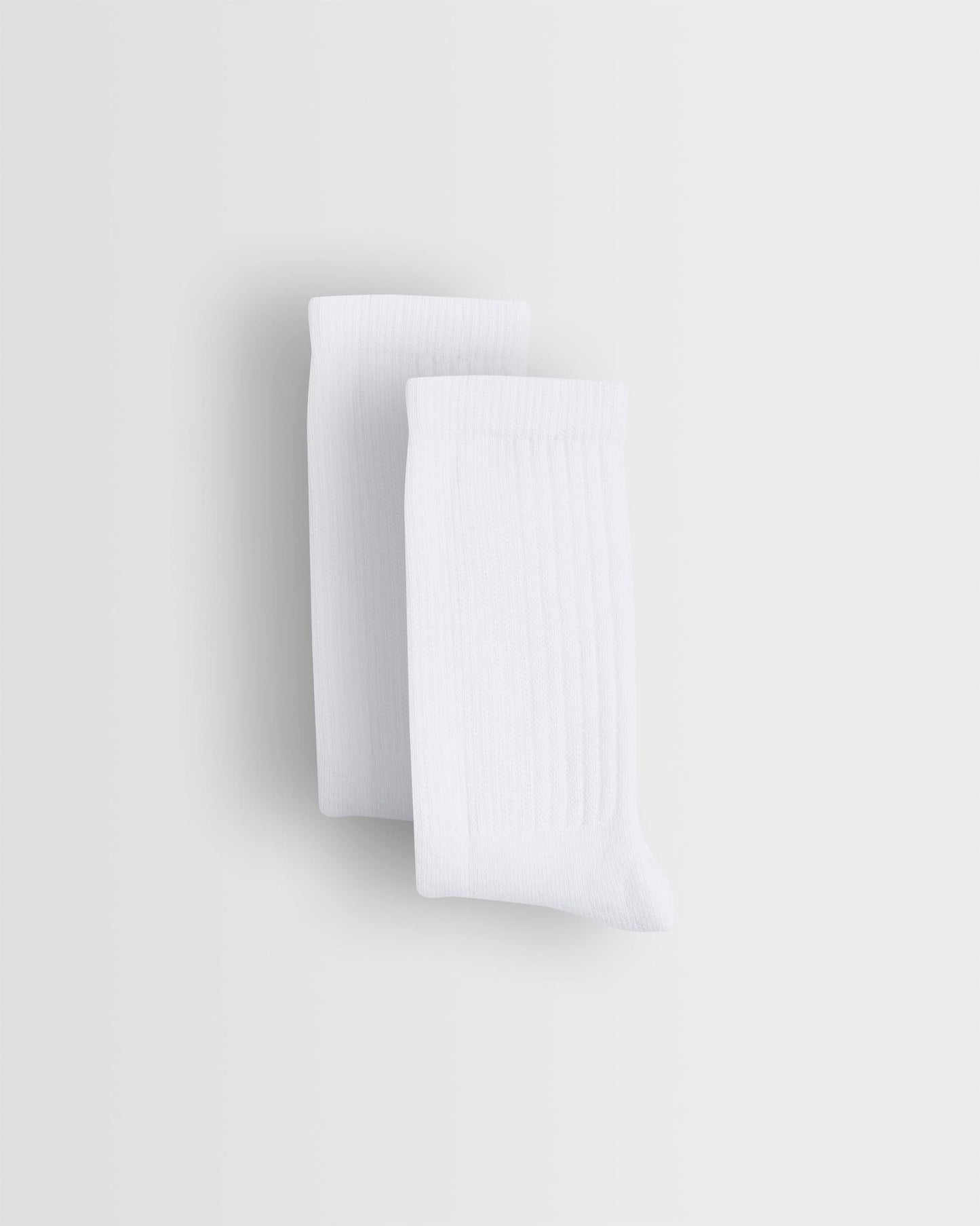 Two white sports socks stacked on top of each other against a light background.