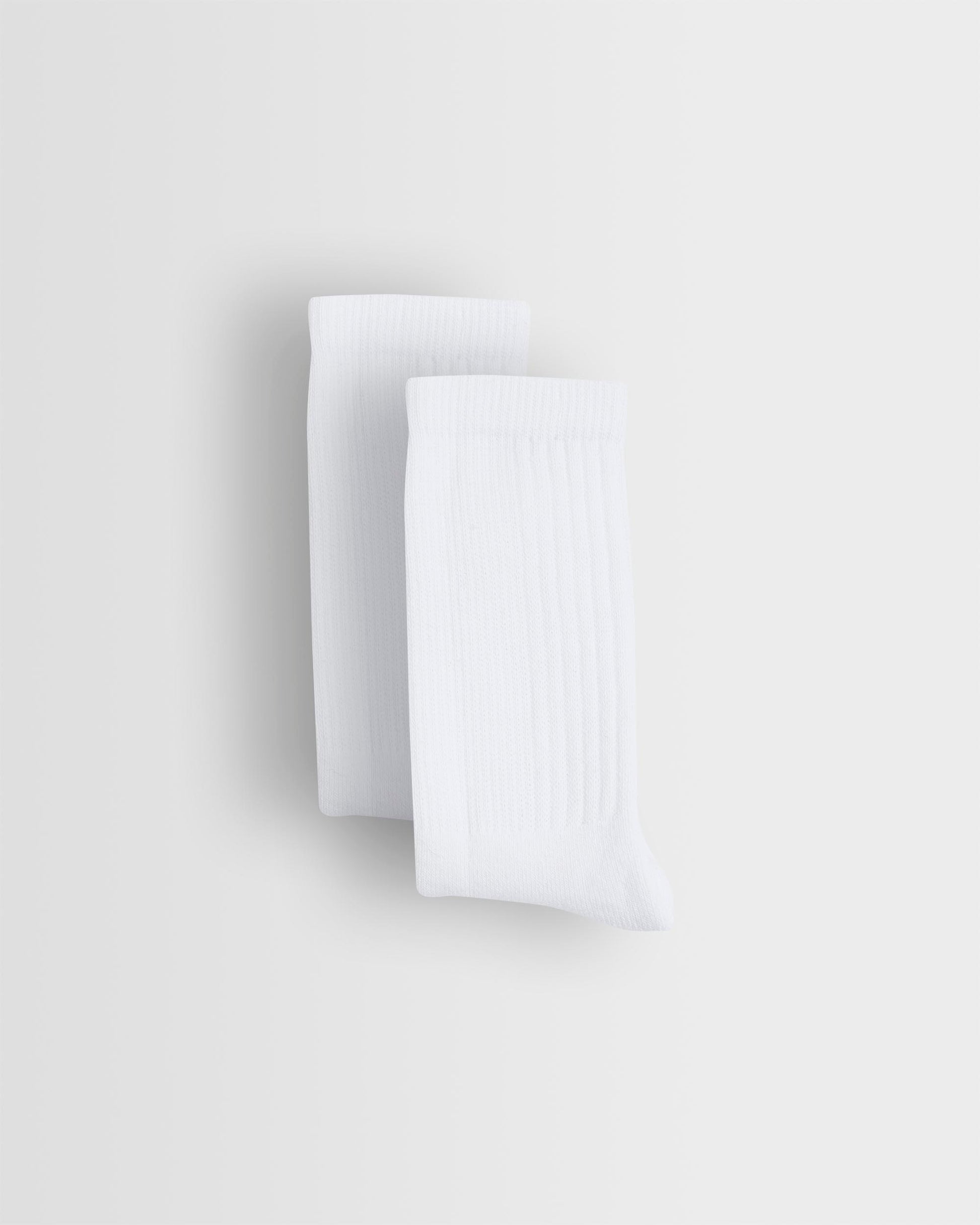 Two white sports socks stacked on top of each other against a light background.