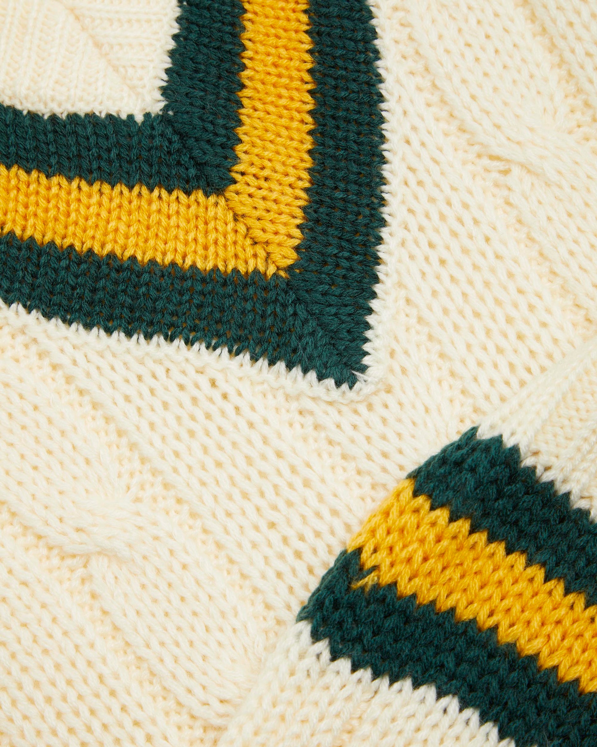 Close up of details on a sleeveless cricket slipover with a V-neck collar, featuring white as the primary color with green and gold stripes on the neck and waist