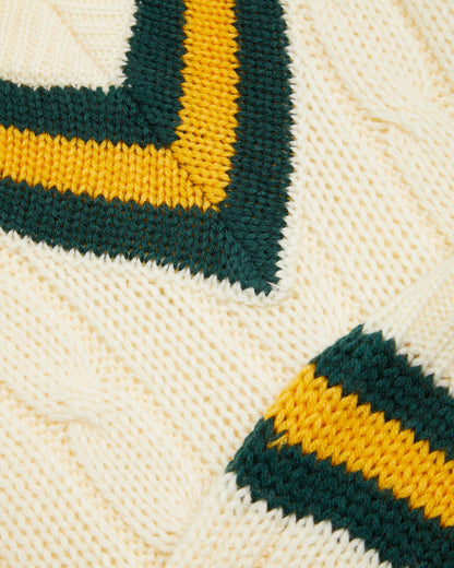Close up of details on a sleeveless cricket slipover with a V-neck collar, featuring white as the primary color with green and gold stripes on the neck and waist