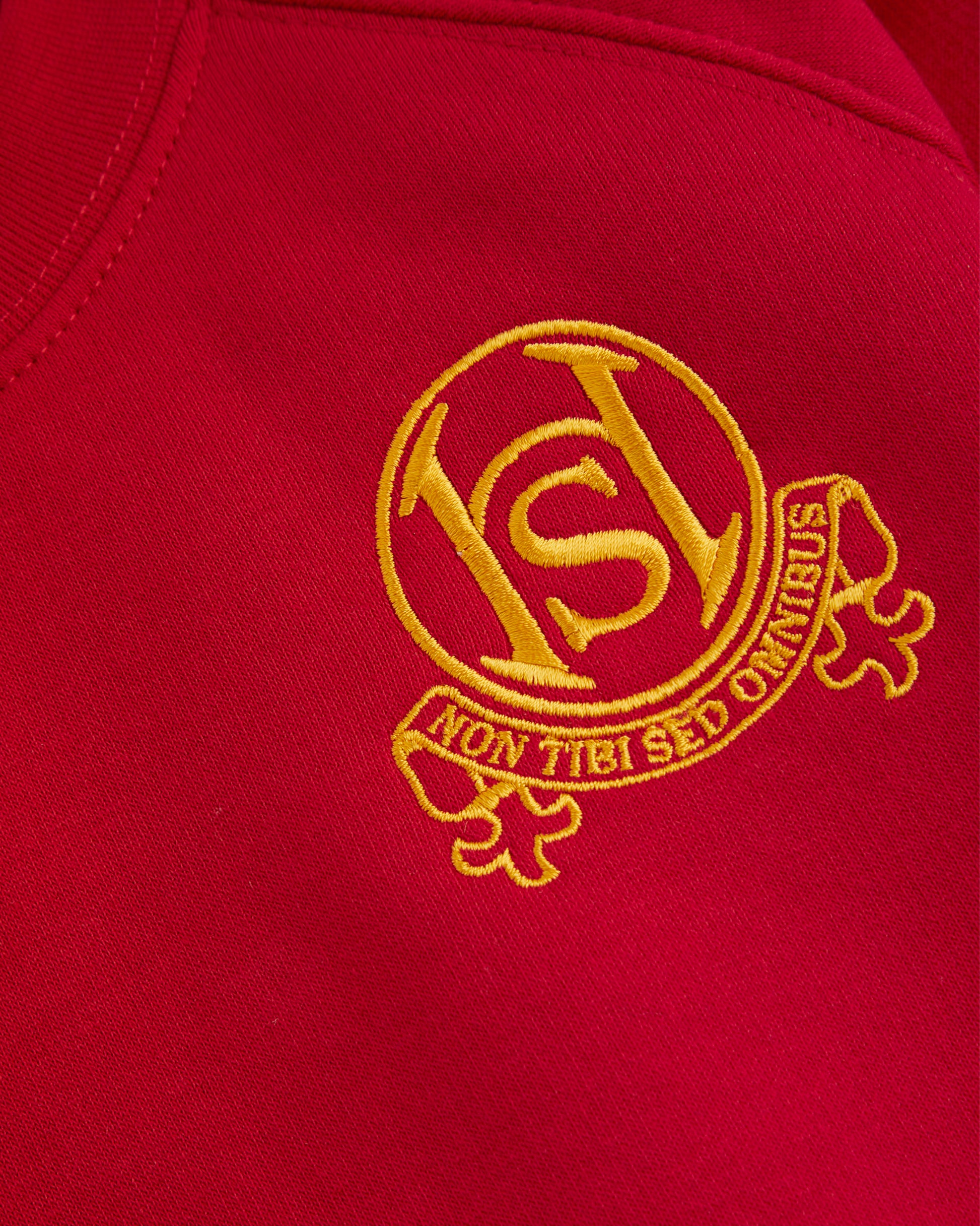 Close-up of a red fabric with a gold embroidered logo and text.