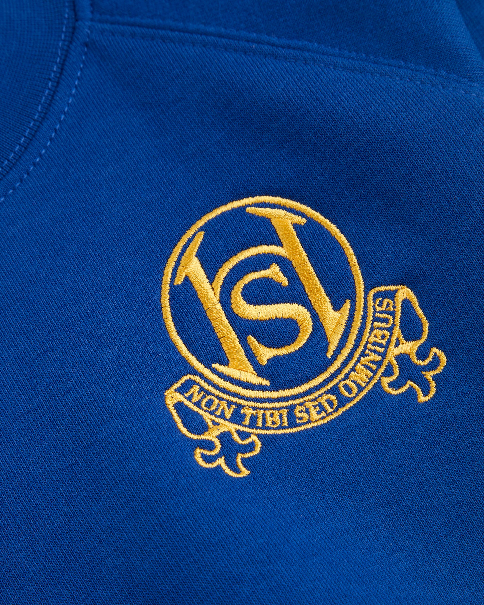 Close-up of a blue fabric with a gold embroidered logo and text.