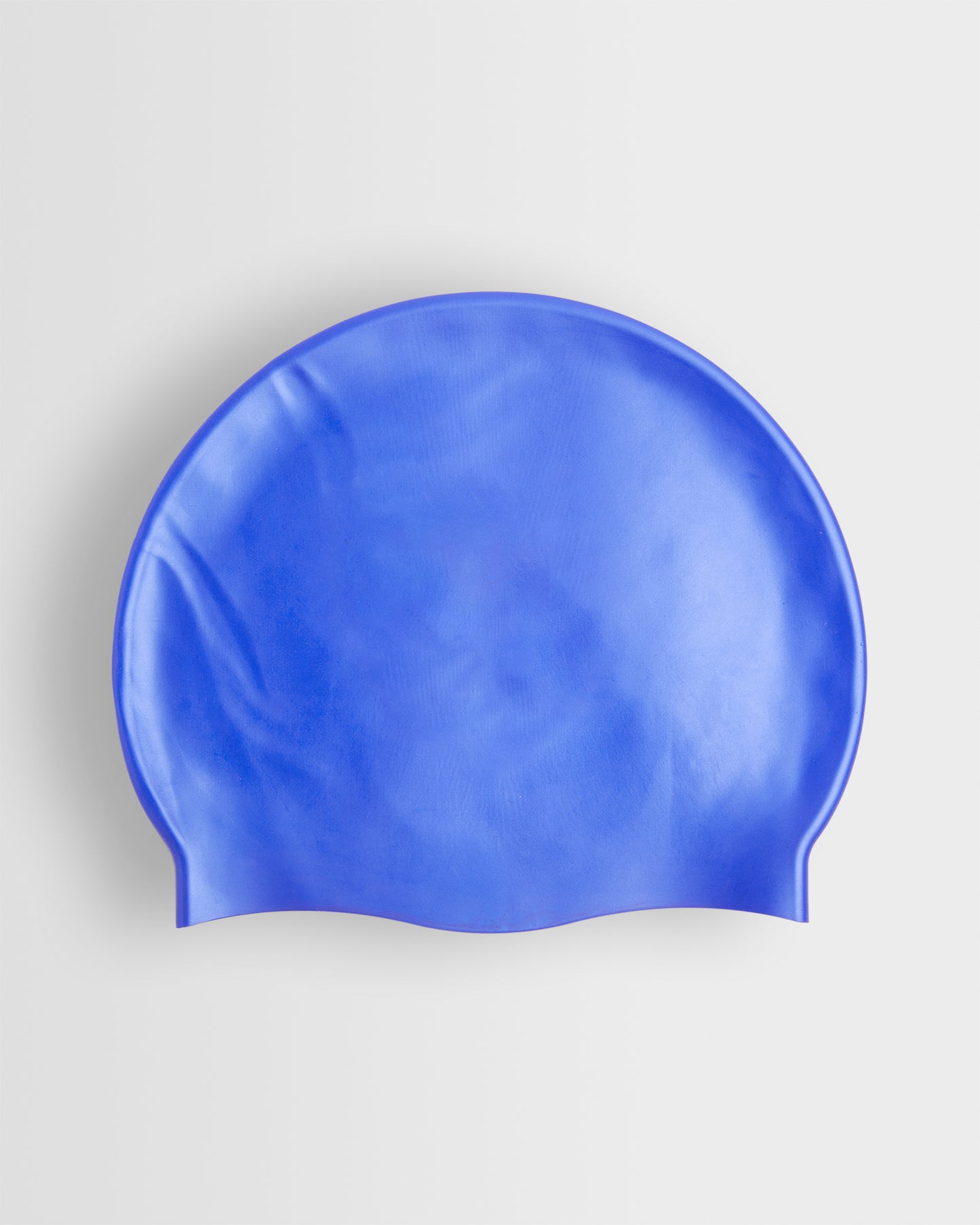 A blue silicone swimming cap placed on a white background.