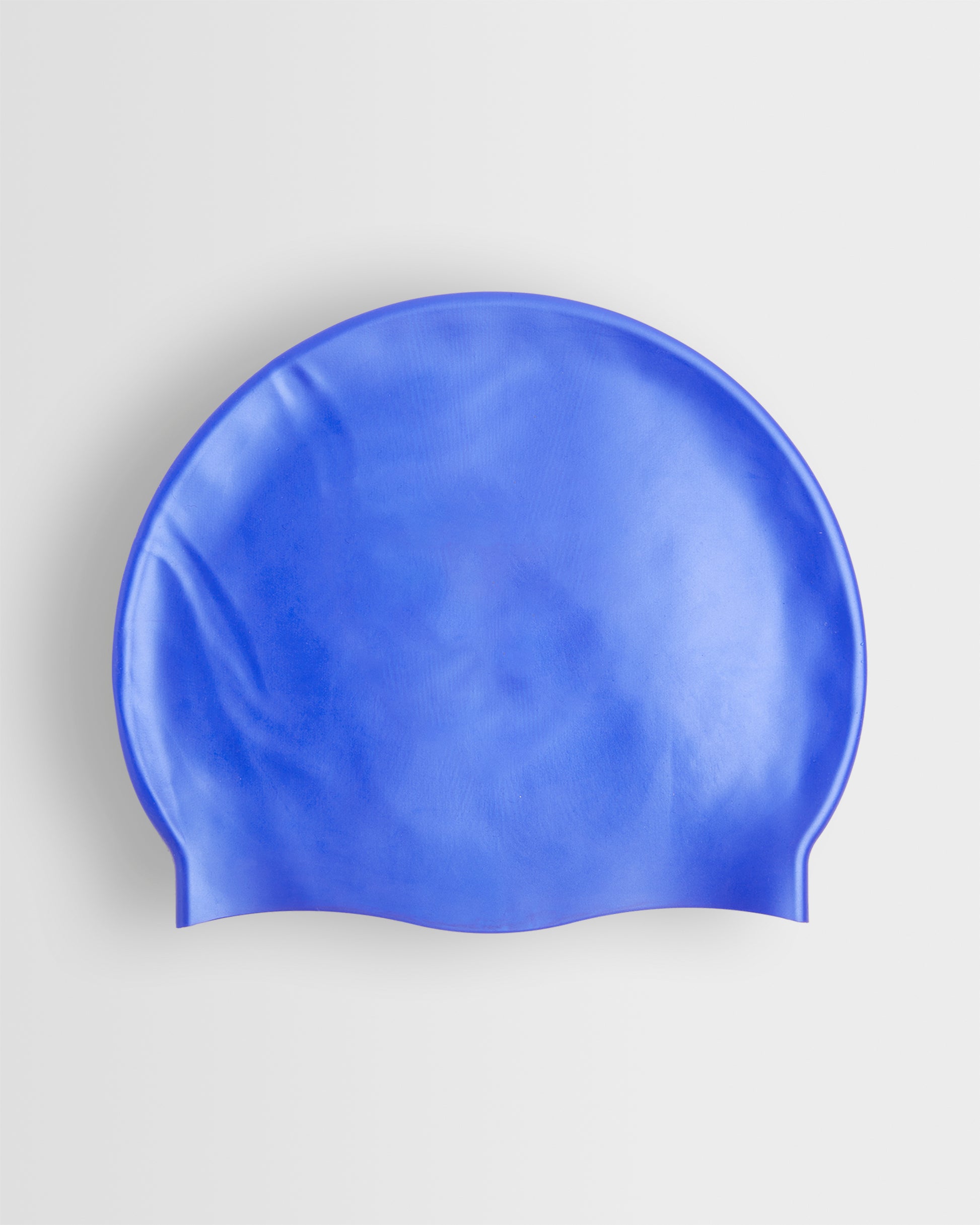 A blue silicone swimming cap placed on a white background.