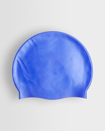 A blue silicone swimming cap placed on a white background.