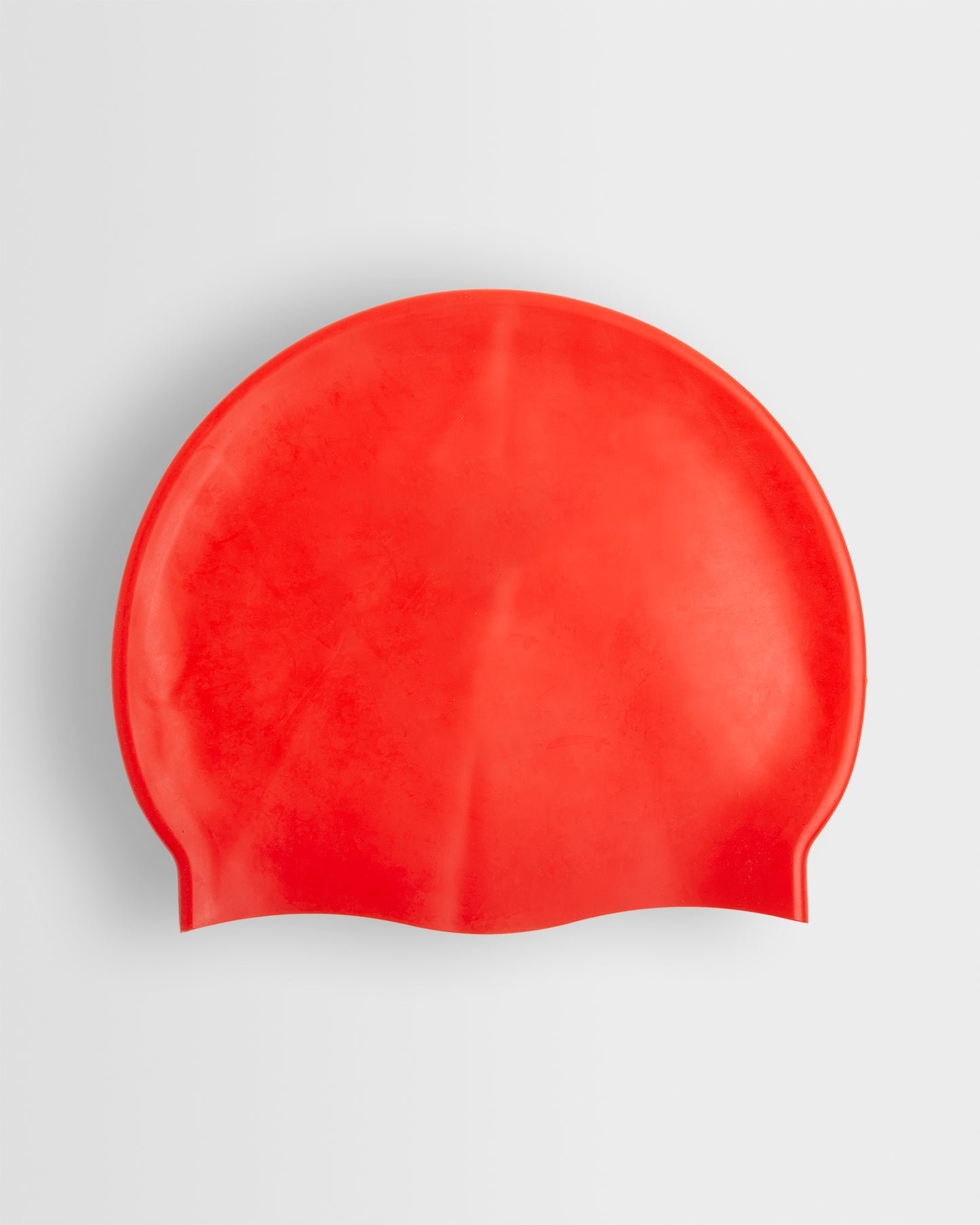 A red silicone swimming cap placed on a white background.