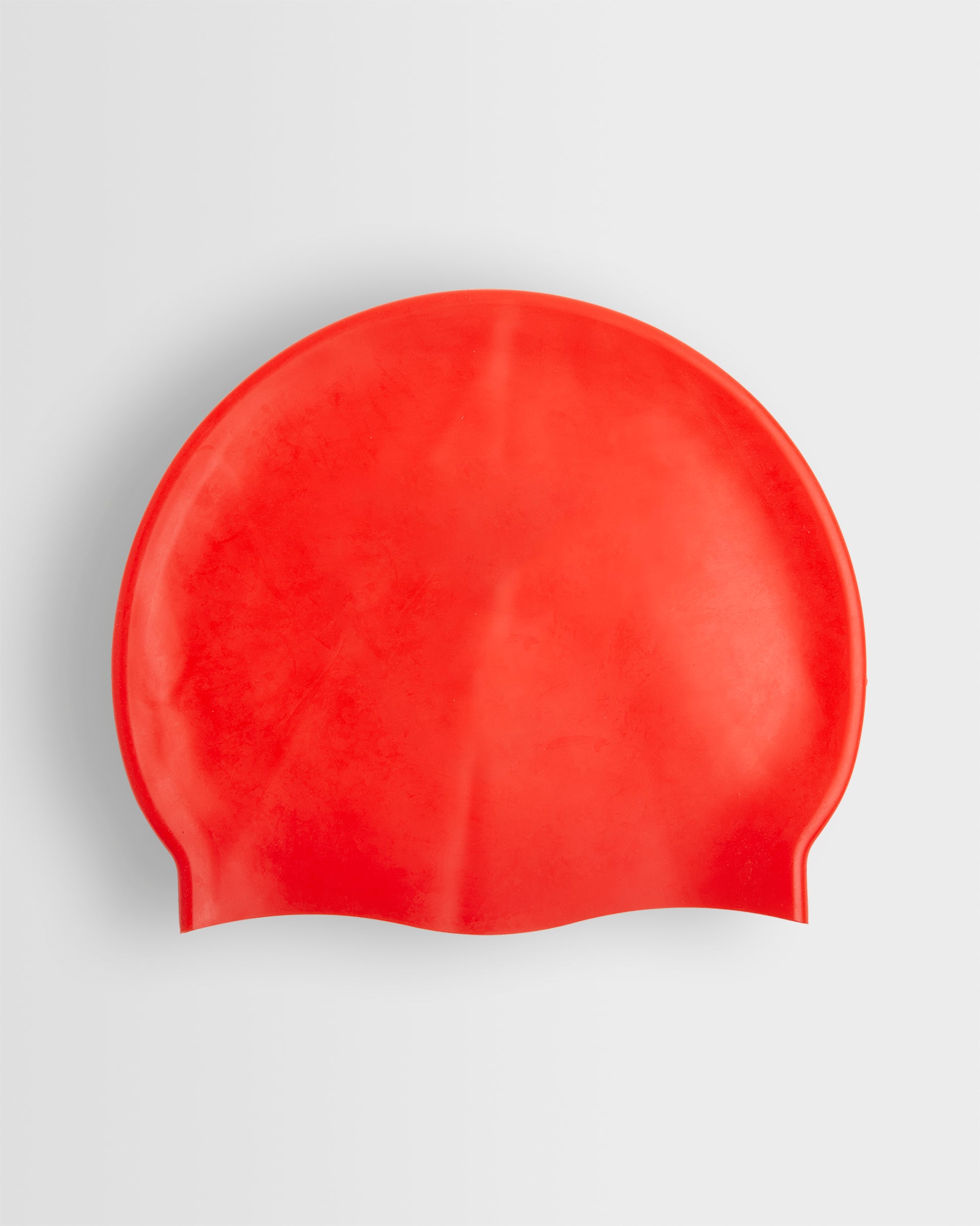 A red silicone swimming cap placed on a white background.