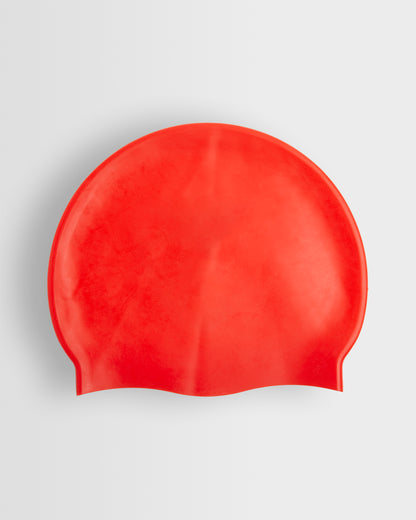 A red silicone swimming cap placed on a white background.