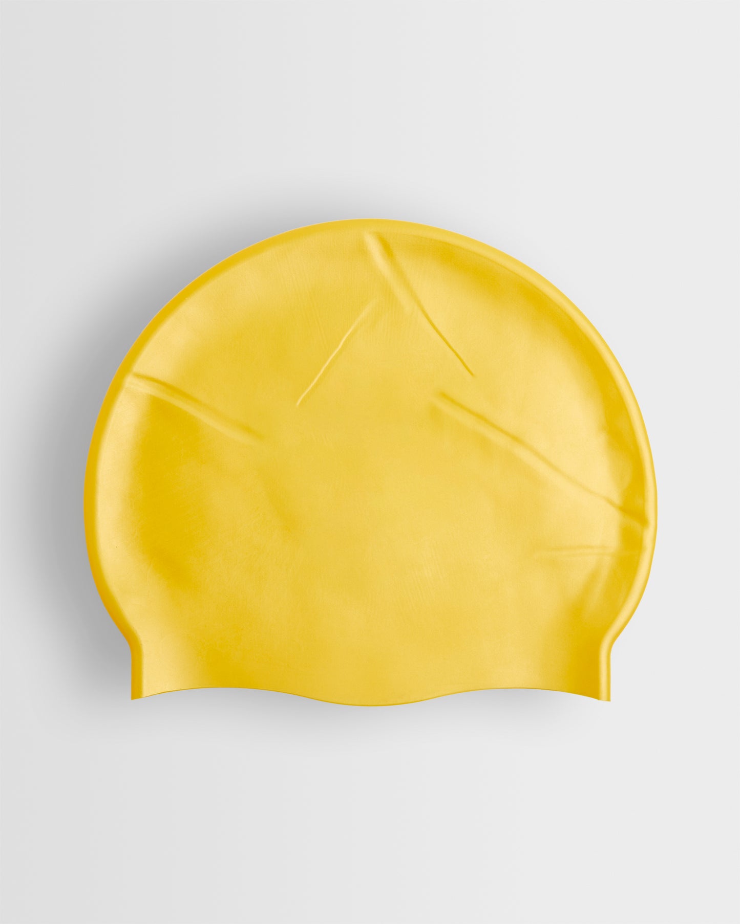 A yellow silicone swimming cap placed on a white background.