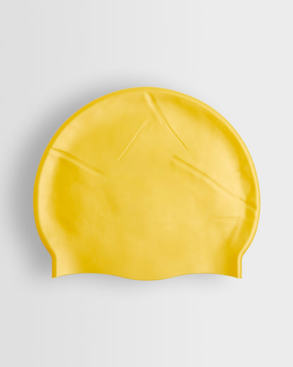 A yellow silicone swimming cap placed on a white background.