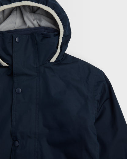 Close up of hood and top left chest of a navy-colored, long-sleeved waterproof coat 