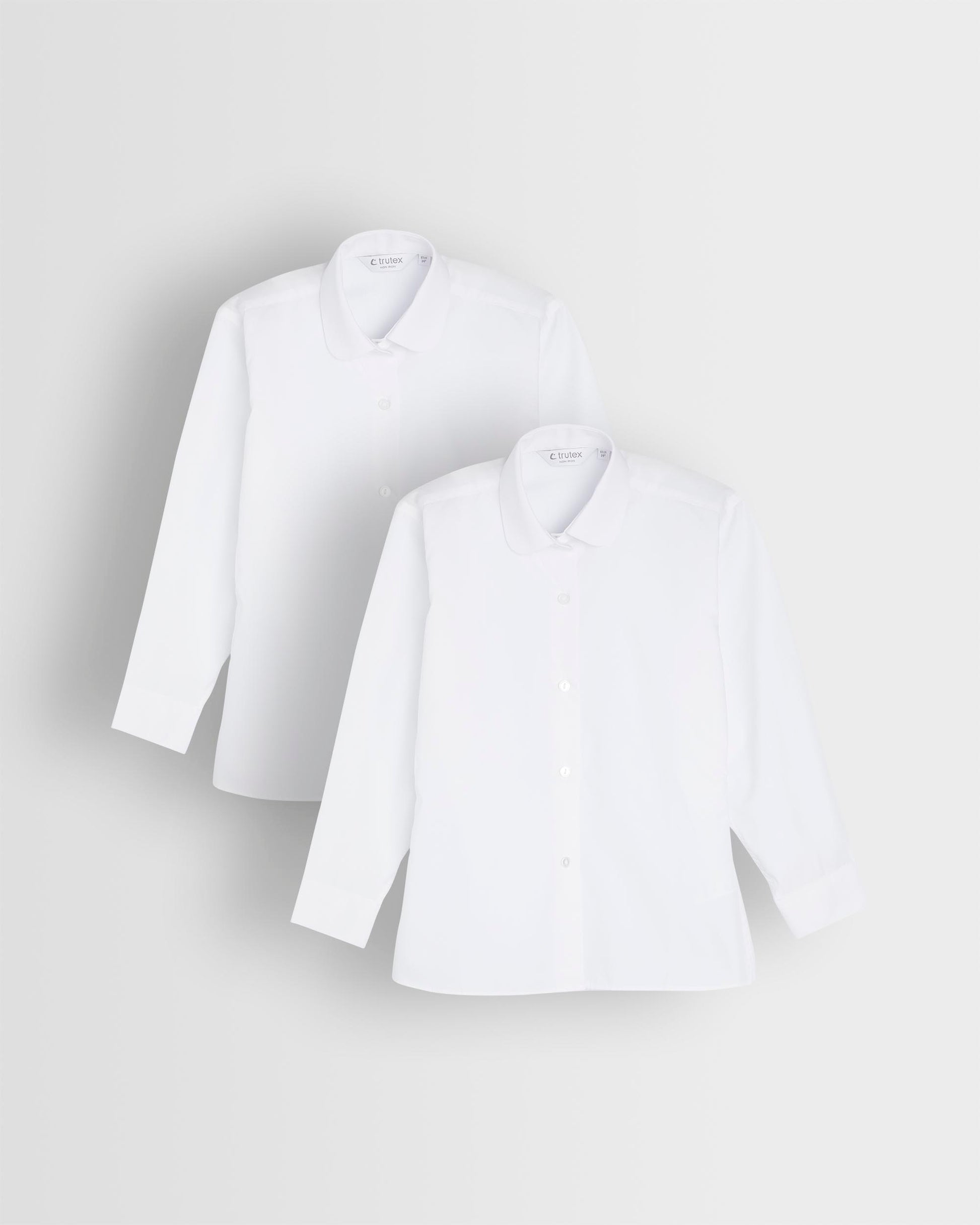 Two long sleeve white blouses with Peter Pan collars laid out flat.