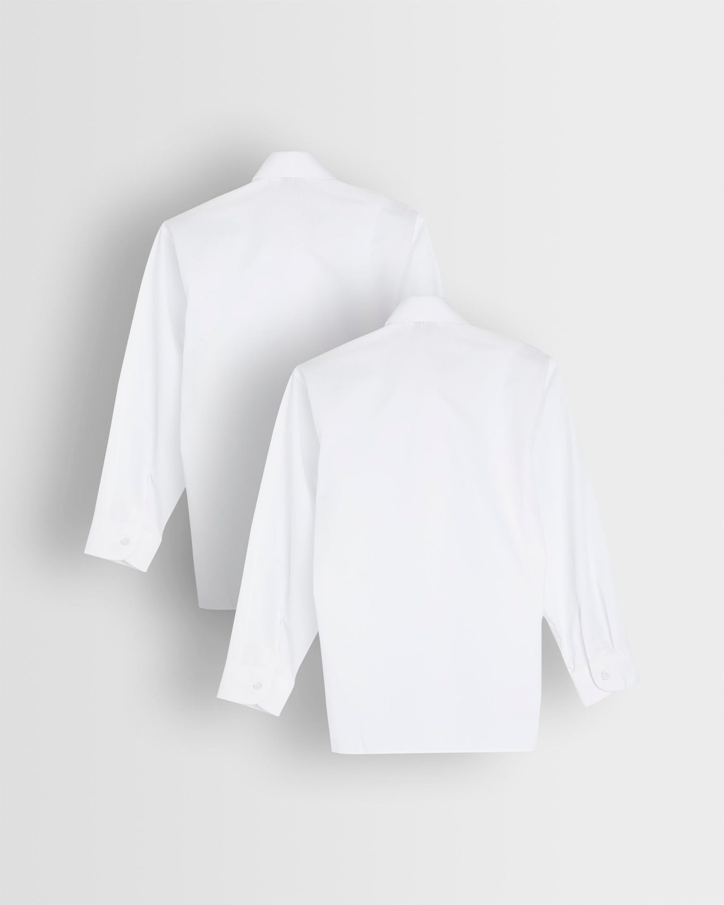 Backs of two long sleeve white blouses with Peter Pan collars laid out flat.