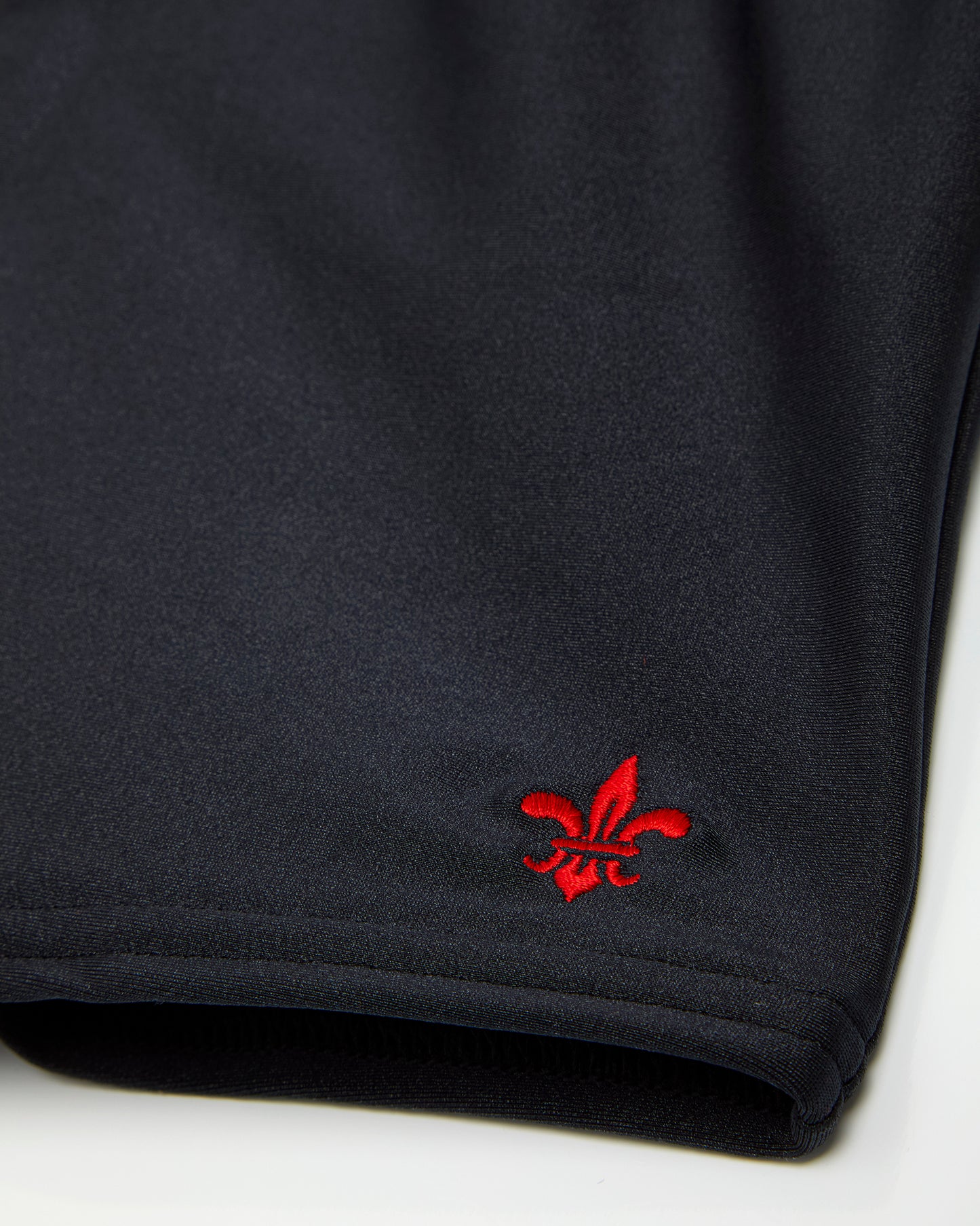 Close up of logo on right leg of black swimming jammers