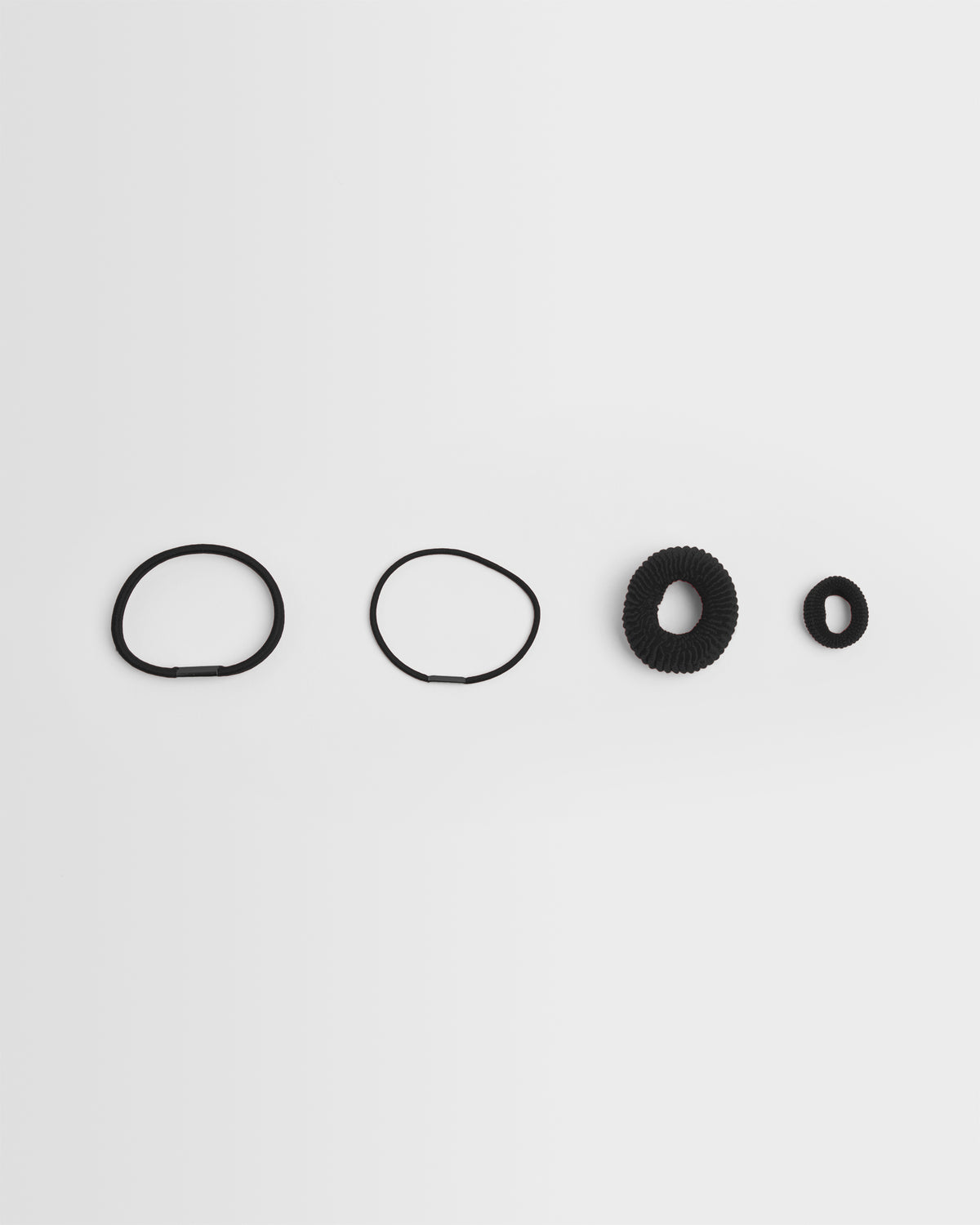 A collection of black hair bands of different sizes arranged in a line on a white background.