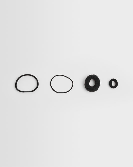 A collection of black hair bands of different sizes arranged in a line on a white background.
